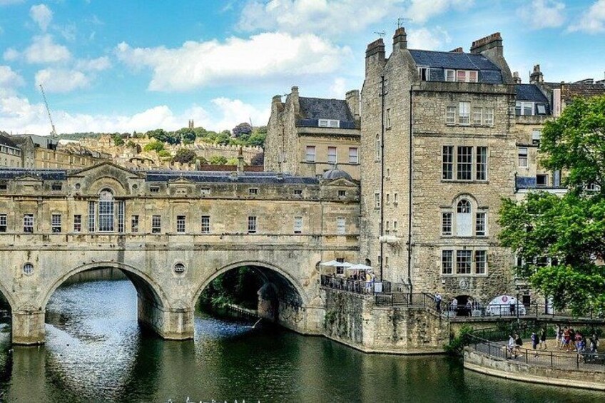 A stone bridge over a river, historic buildings, and a tree-lined promenade. 3