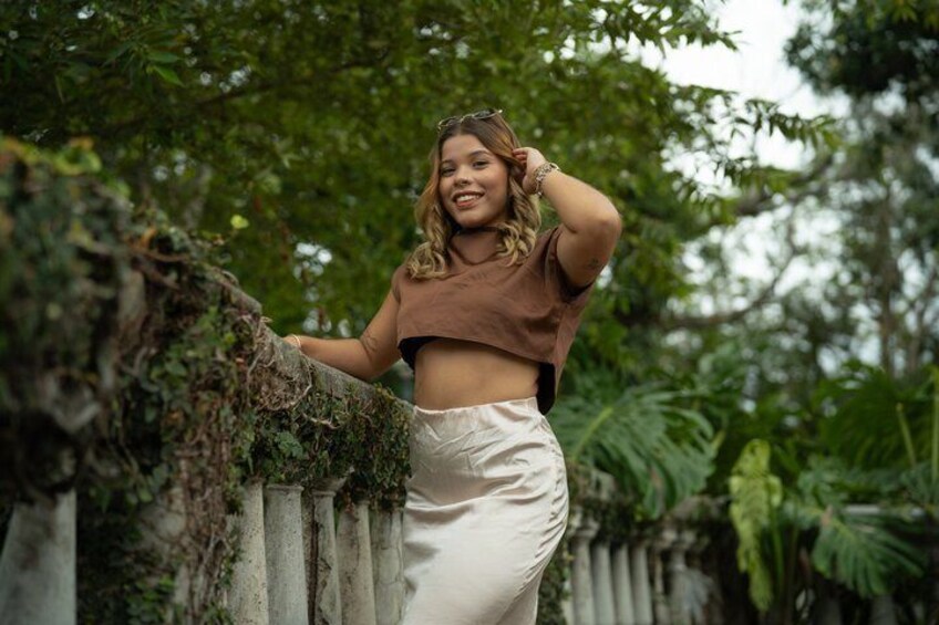 A person leaning on a fence with greenery in the background. 2