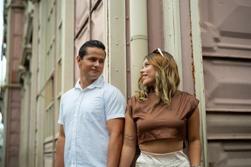 Two people standing by a building with a metal pipe and a window. 3