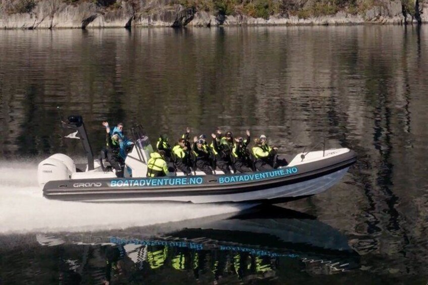 A boat with people wearing life jackets and helmets, labeled 'BOATADVENTURE.NO,' moving on water. 3