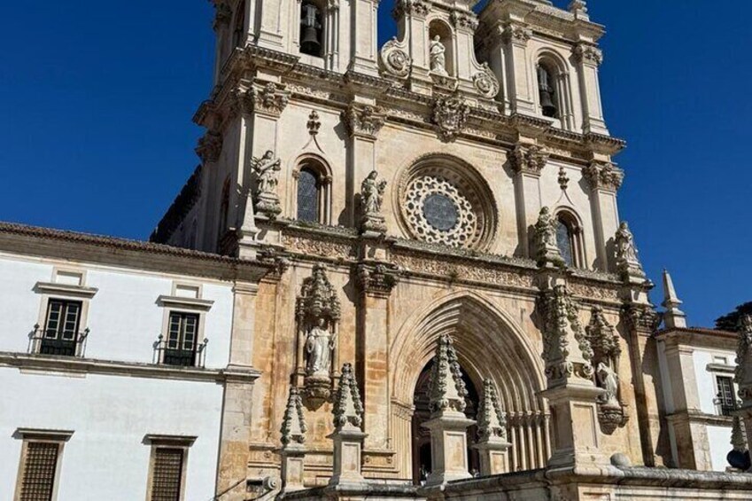 A historic cathedral with a large circular window, intricate stone carvings, and a bell tower. 1
