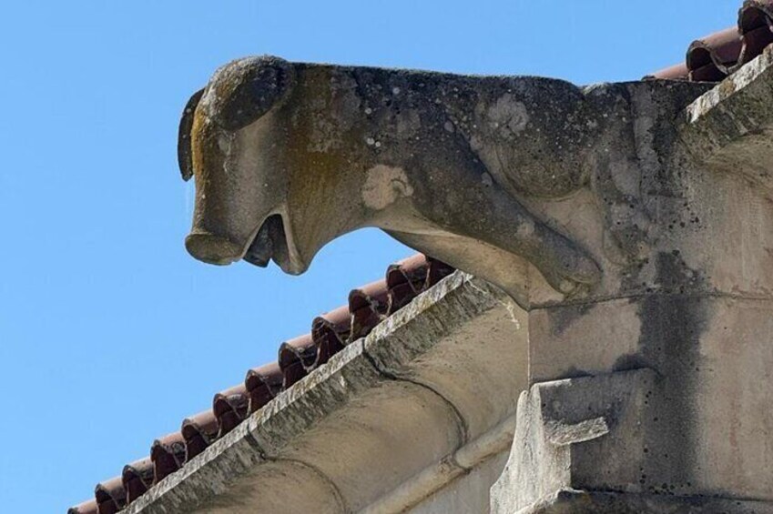 A weathered stone lion statue on a building's roof. 4
