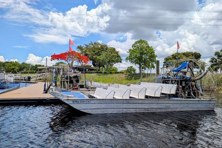 A docked boat with a covered seating area and a red flag. 2