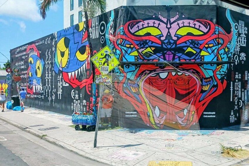 A colorful mural on a building with various designs and text. 3