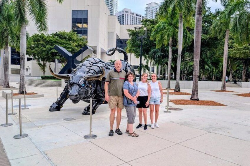 A bull sculpture, palm trees, and a modern building in the background. 5