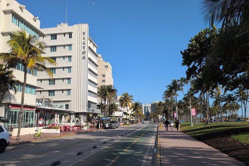 A city street with palm trees, a building with a sign, and a clear blue sky. 2
