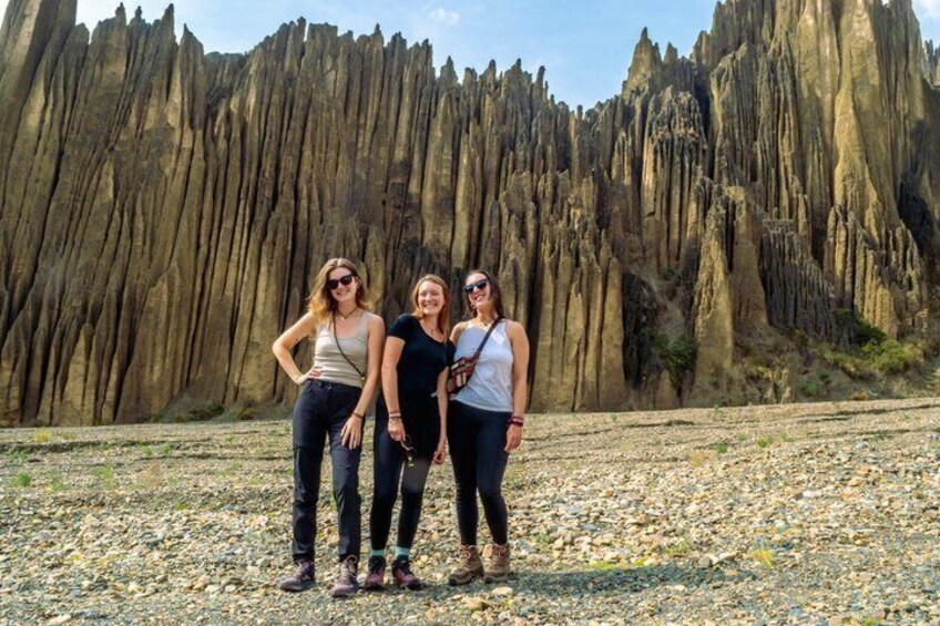 Three people standing in front of a rock formation. 1