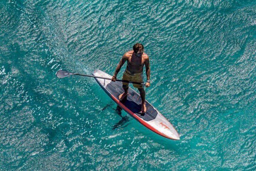 A person paddleboarding on turquoise water. 1