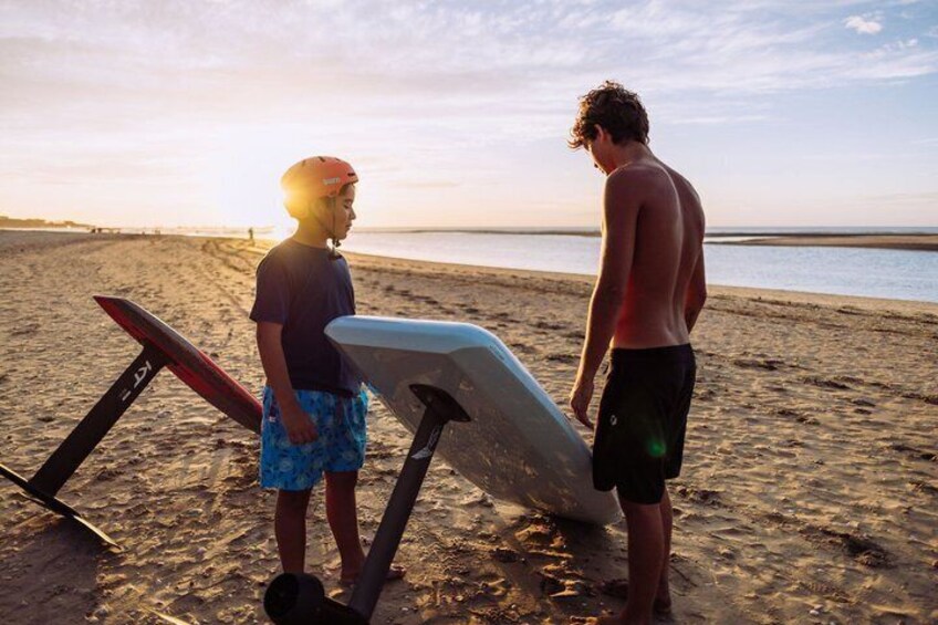 Two people standing on a beach with surfboards, a sunset in the background, and a calm sea. 5