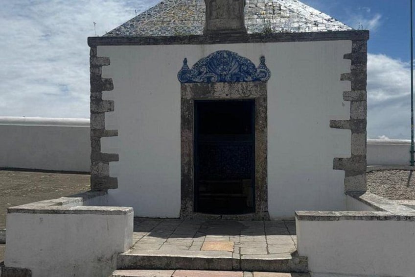A small white building with a tiled roof and a blue decorative element above the entrance. 5