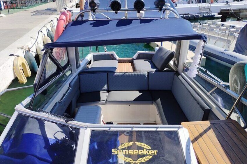 A boat with a blue canopy, seating area, and a logo 'Sunseeker' on the deck. 2