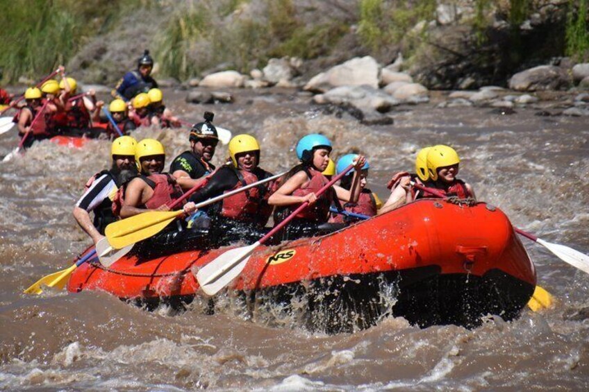 A group of people in a red raft navigating a river with rapids. 4