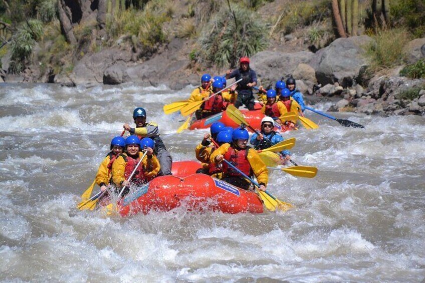 A group of people rafting down a river in a red raft. 1