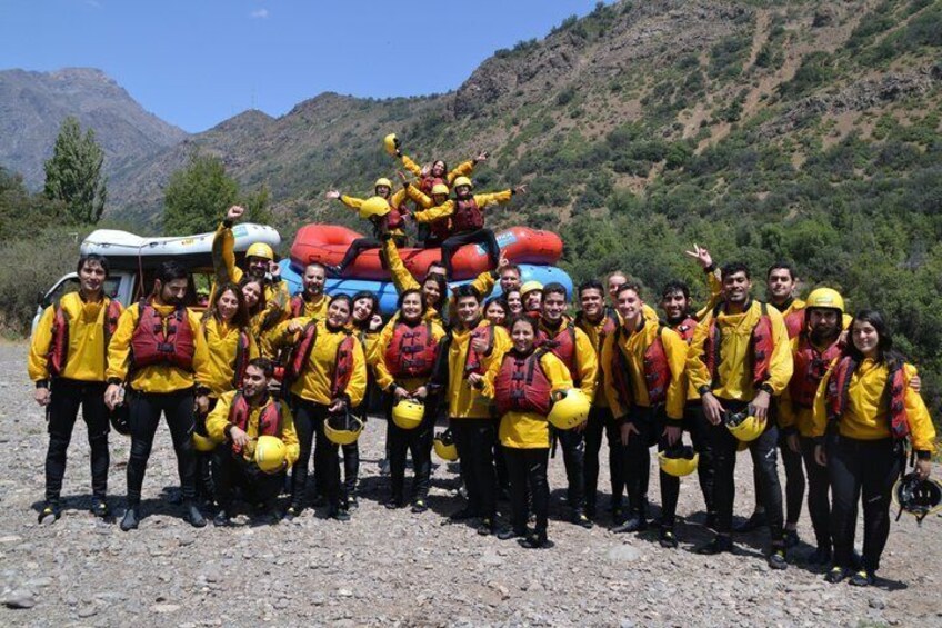 A group of people in yellow jackets posing with inflatable rafts in a mountainous area. 3