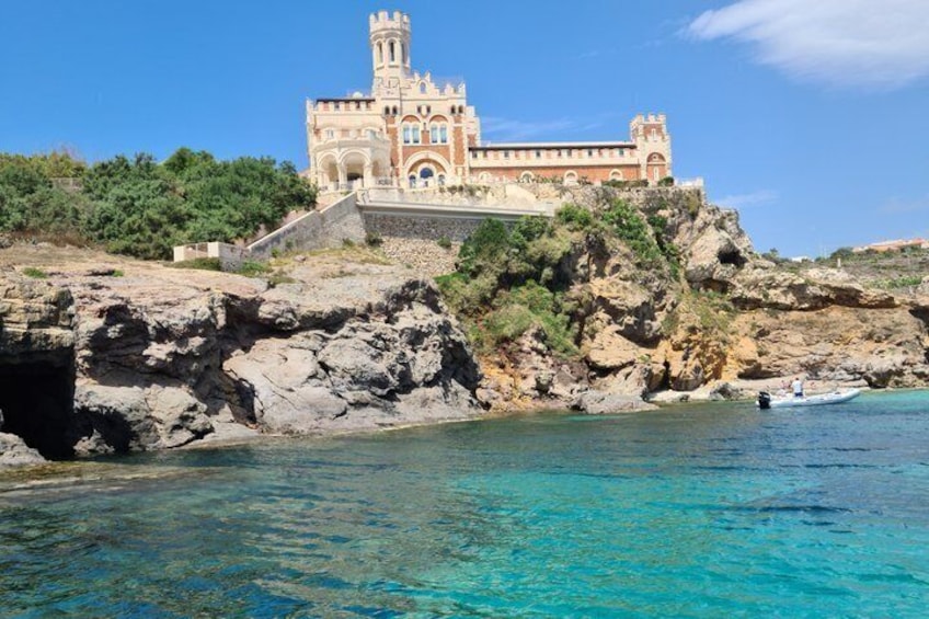 A coastal building with a tower, surrounded by clear blue waters and rocky cliffs. 4