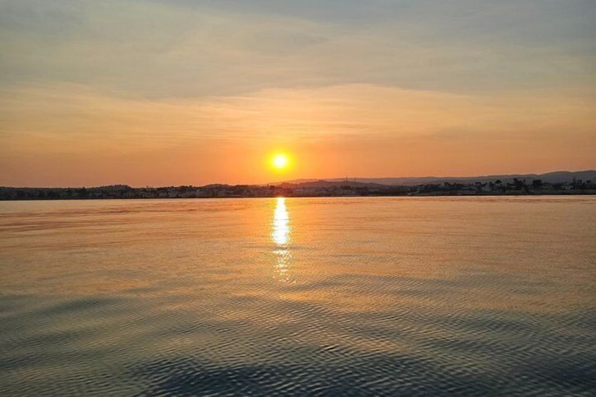 A sunset over a calm body of water with a distant shoreline. 3