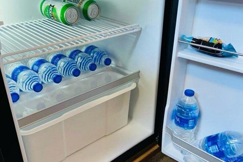 A refrigerator with multiple water bottles and a few cans on the shelves. 1