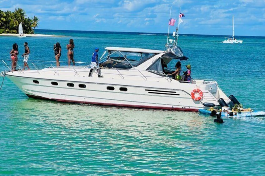 A white yacht with a red stripe, people on board, and a lifebuoy. 1