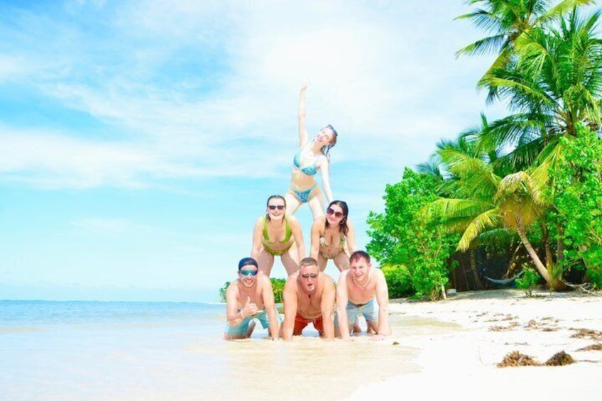 A group of people on a beach with palm trees and ocean in the background. 3