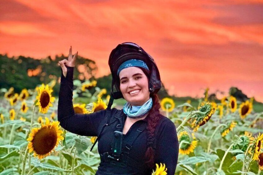 A person in a field of sunflowers with a sunset in the background. 5