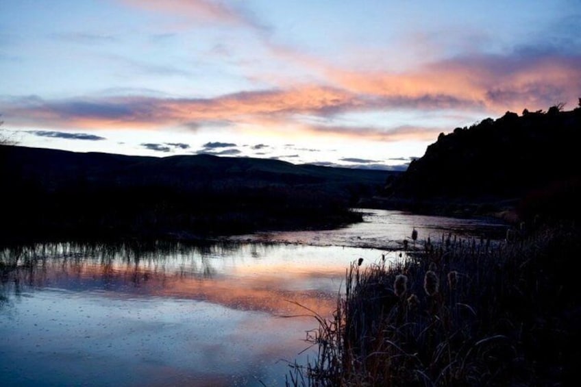 A calm lake at dusk with a sunset reflecting on the water, surrounded by hills. 4