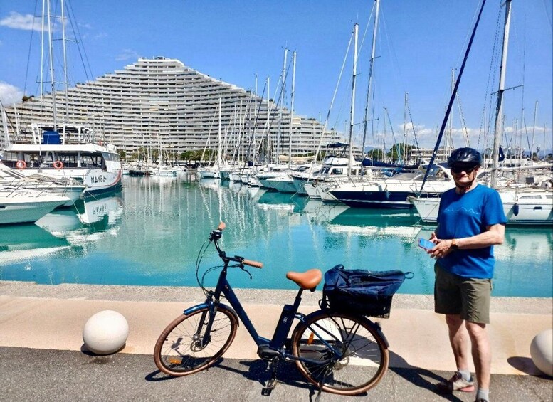 A marina with boats, a cyclist, and a large cruise ship in the background. 2