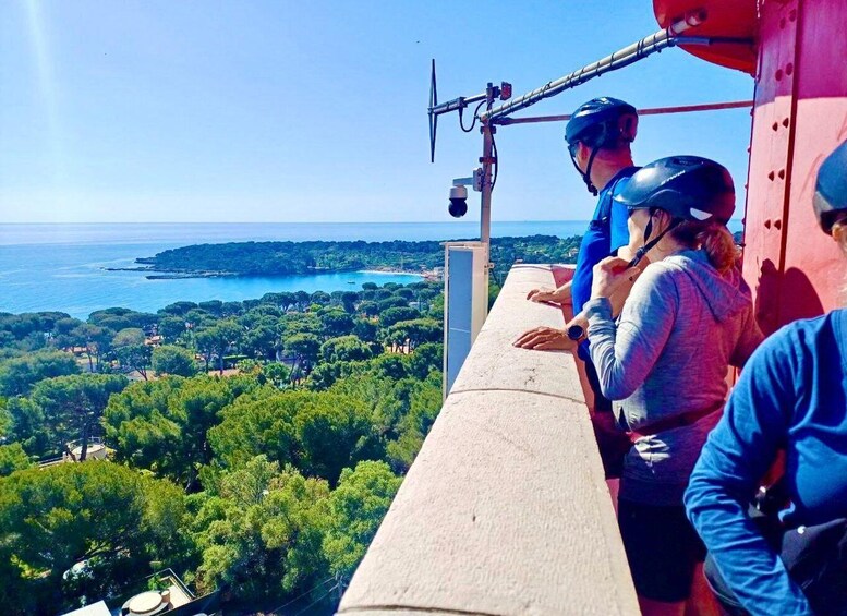 A group of people on a high platform overlooking a coastal landscape with trees and a view of the sea. 4
