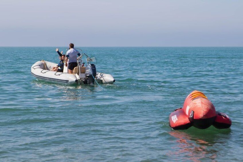 A small inflatable boat on calm water with a person standing at the stern. 3