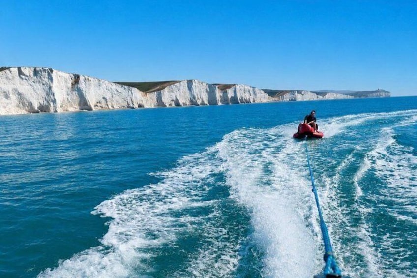 A person wakeboarding on a body of water with cliffs in the background. 1