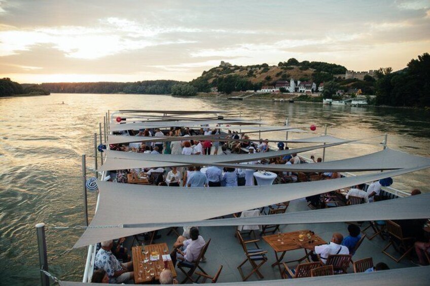A boat with people dining and sightseeing, surrounded by water and hills. 4