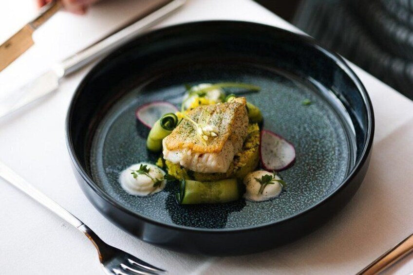 A plate of food with a fish fillet, green vegetables, and a dark sauce. 5