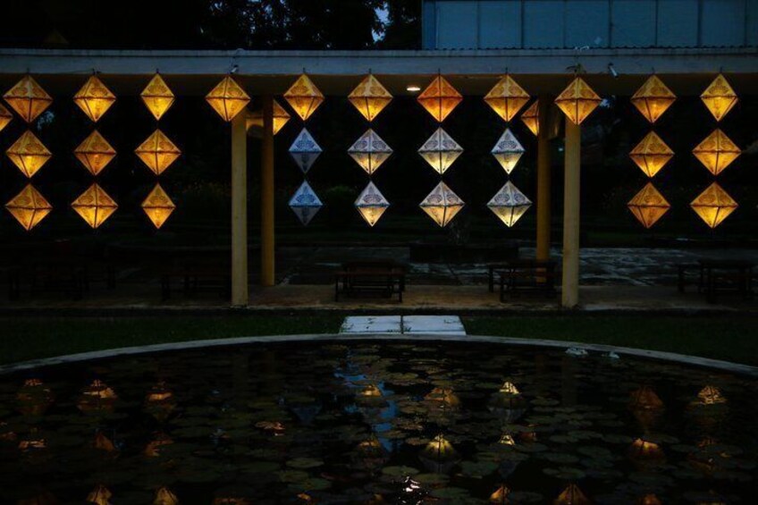 A pavilion with a series of illuminated lanterns and a reflective water feature. 2