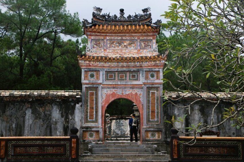 A traditional Chinese gate with intricate designs and a person standing in front. 1