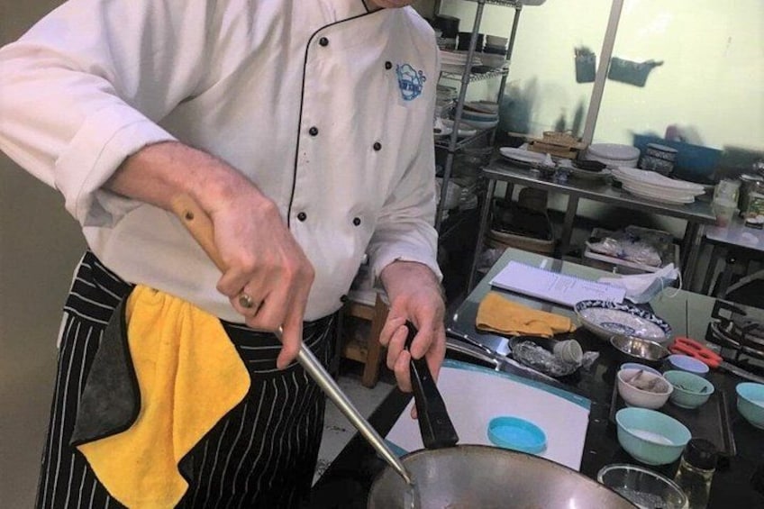 A chef in a kitchen, stirring a pot with a wooden spoon. 2