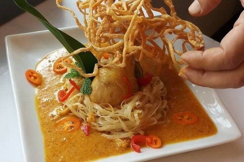 A dish with noodles, a piece of meat, and sliced red chili peppers on a white plate. 5