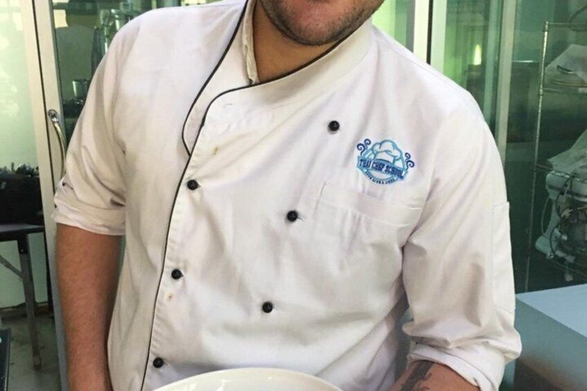 A chef in a white uniform with a logo, holding a plate. 4