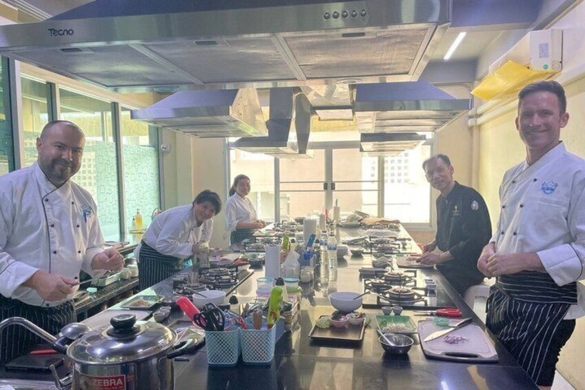 A professional kitchen with chefs preparing food, stainless steel appliances, and cooking utensils. 1