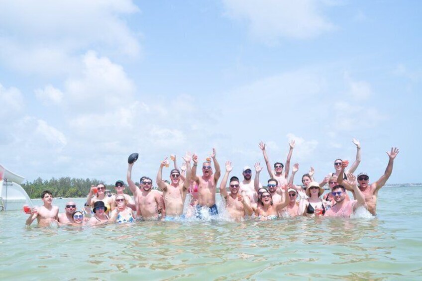 A group of people in a body of water, some wearing hats and sunglasses, with a clear sky above. 3