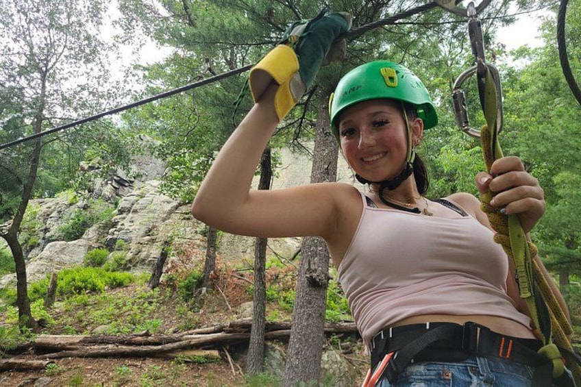 A person in a forested area with a rope, wearing a helmet and gloves. 2