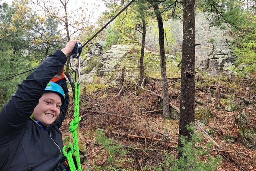 A person climbing a tree with a green rope. 4