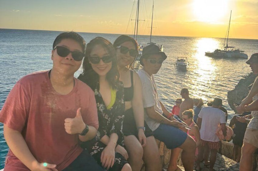 A group of people on a boat with the sun setting in the background. 5