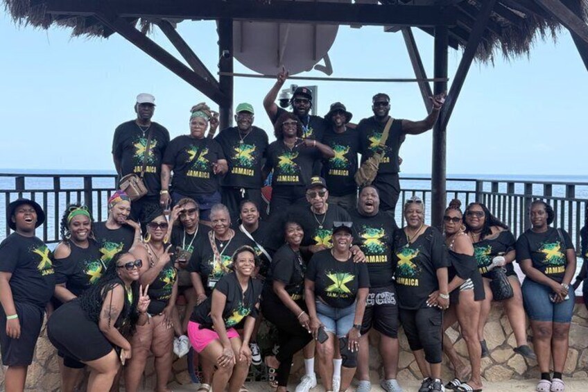 A group of people posing in a gazebo with a view of the ocean. 1