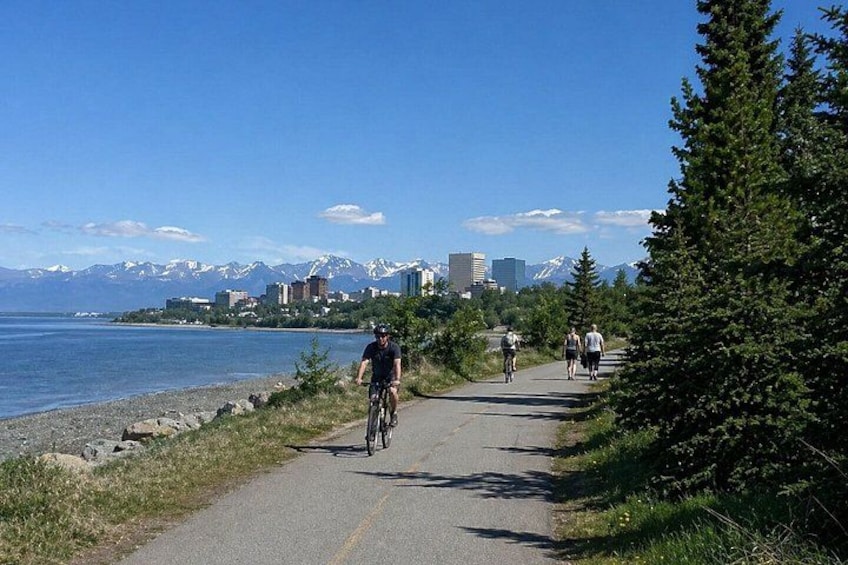 A paved bike path alongside a body of water with mountains in the background. 4