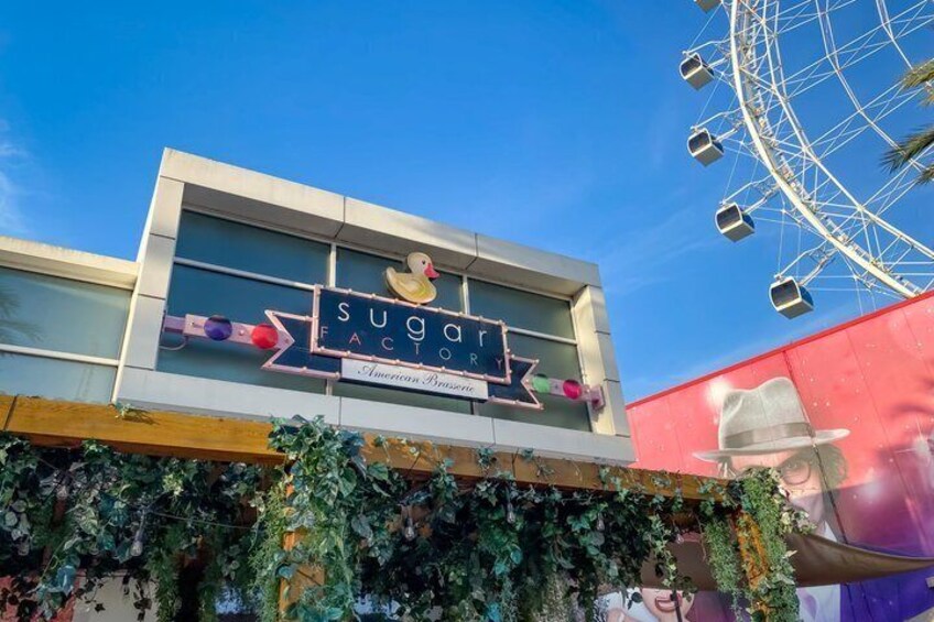 A building with a sign that reads 'Sugar Factory American Pizzeria' and a Ferris wheel in the background. 5