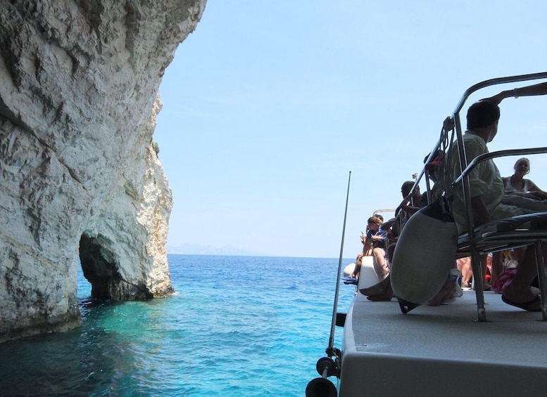 Un bateau avec des personnes à bord, naviguant près d’une côte rocheuse. 2
