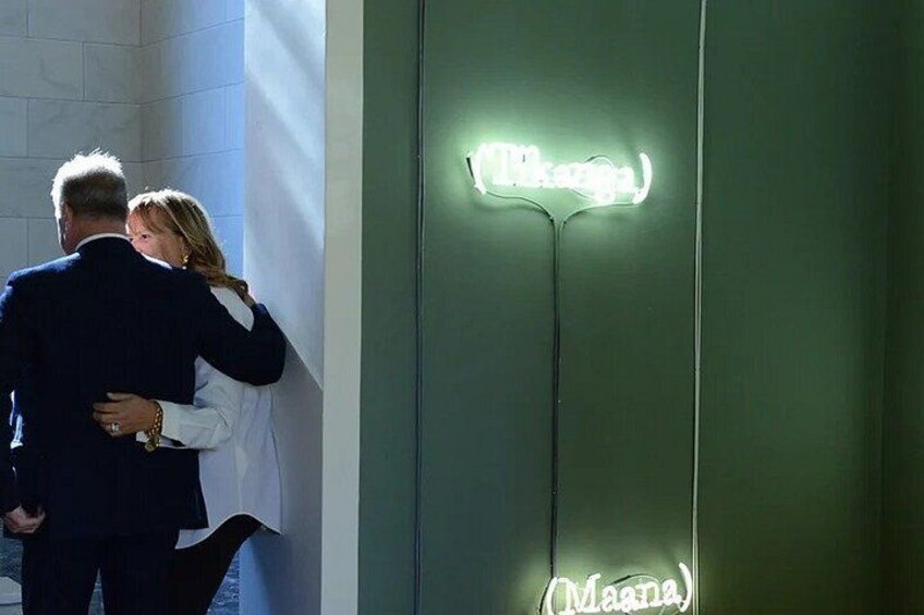 A couple embracing, a neon sign with the word 'Maana,' and a green wall. 5
