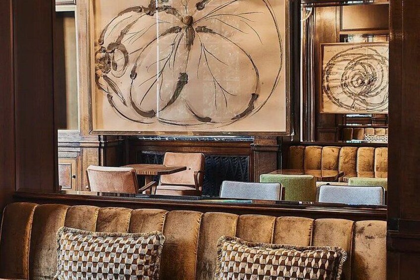 A cozy seating area with a brown upholstered bench, patterned cushions, and a large abstract painting on the wall. 4