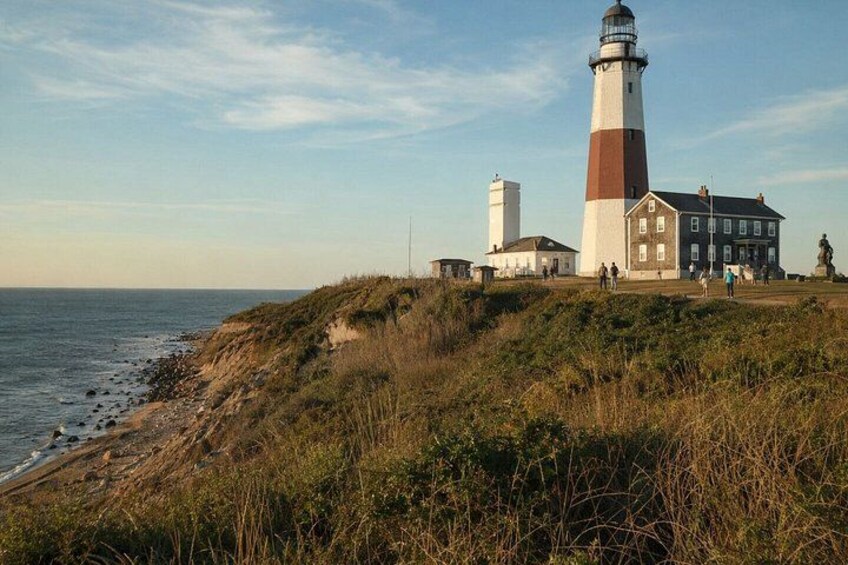 A lighthouse, a building, and a grassy cliff by the sea. 1