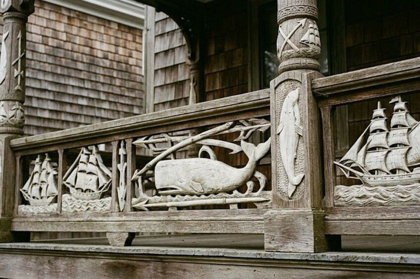 A wooden balcony with intricate carvings of ships, a whale, and a shipwreck. 4