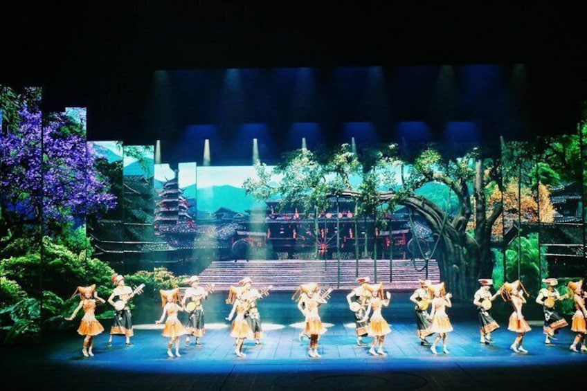 A stage with dancers in yellow dresses, a pagoda, and a traditional Japanese garden. 2